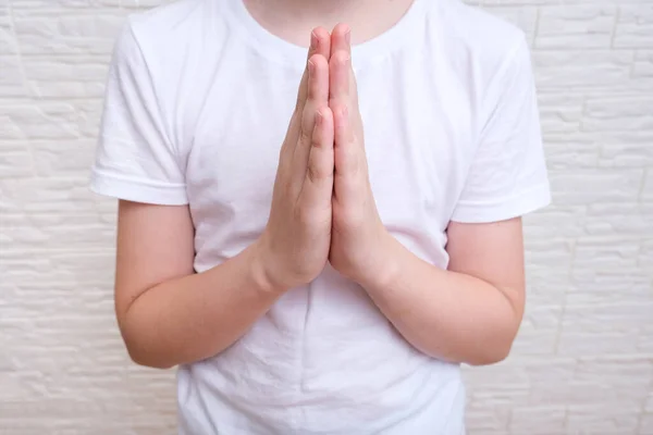Ένα αγόρι δείχνει ευγνωμοσύνη χειρονομία σε λευκό φόντο, είναι αισιόδοξος, ενώ προσεύχεται — Φωτογραφία Αρχείου