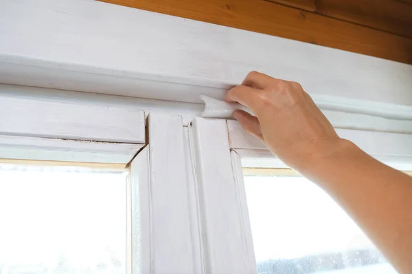 暖かい熱漏れやドラフトを防ぐために女性の手絶縁古い窓 冬と寒い天候のための家を準備 ストックフォト