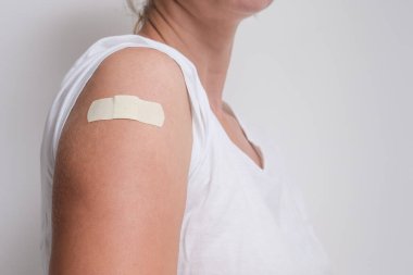 Aşı enjekte edildikten sonra kolunu bandajla gösteren bir kadın. Corona virüsünden aşılanmak, covid-19, uzayı kopyala.