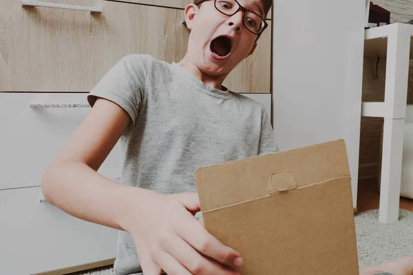 Ενθουσιασμένο Αγόρι Κάθεται Ένα Χαλί Και Ανοίγει Ένα Κουτί Ένα — Φωτογραφία Αρχείου