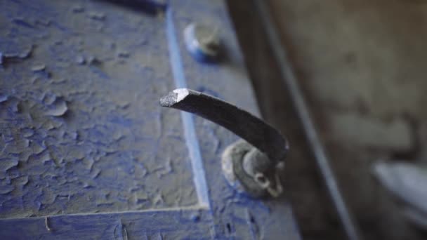 Alte Türklinke. Holztüren mit einem Metallgriff sind mit Staub bedeckt. Unbewohntes Haus. Schmutzige blaue Haustüren zum Haus. Ein mystischer Ort.
