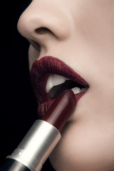 Vrouw toepassen van rode lippenstift op zwarte achtergrond — Stockfoto