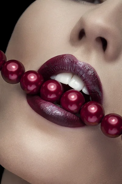 Mujer mordiendo con labios rojos perlas rojas — Foto de Stock