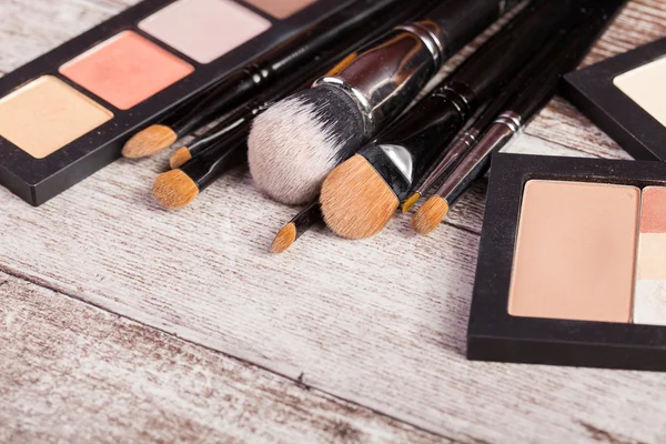 Maquiagem escovas ao lado de produtos cosméticos — Fotografia de Stock