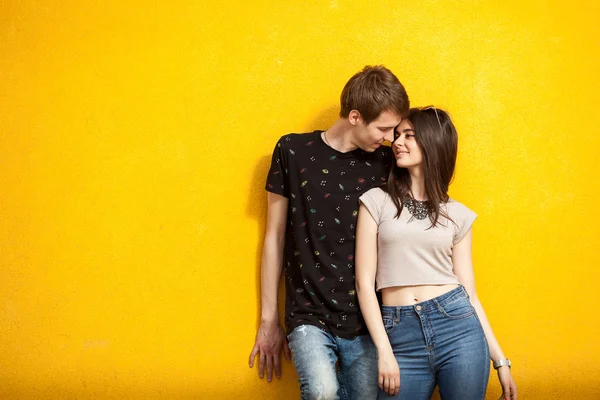 Young inlove couple on yellow wall — Stock Photo, Image