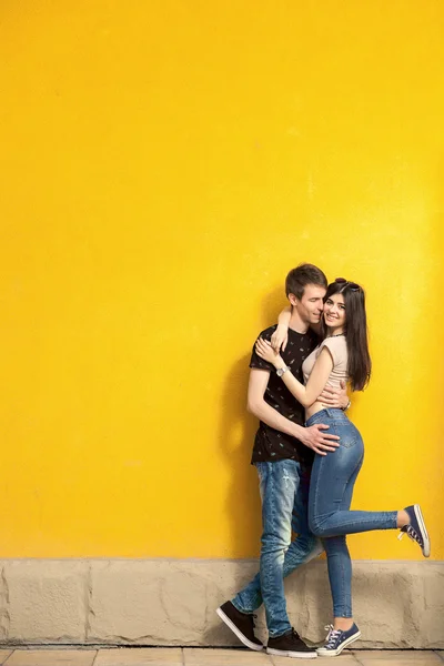 Sonriendo feliz pareja en la pared amarilla —  Fotos de Stock