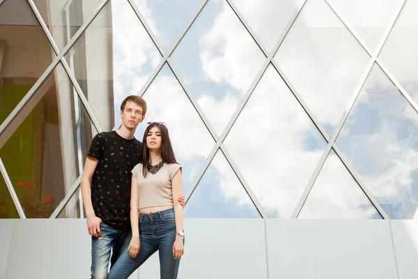 Beautiful couple posing cool in front of glased office building — Stock Photo, Image