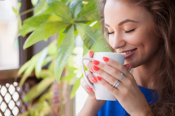 Woman with closed eyes enjoying a cup of coffee