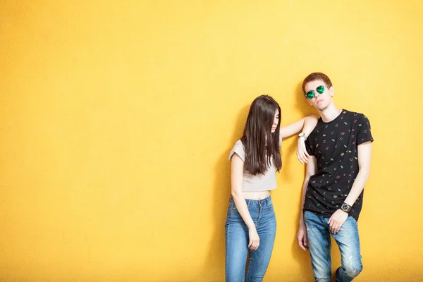 Cool olhando jovem casal na parede amarela — Fotografia de Stock