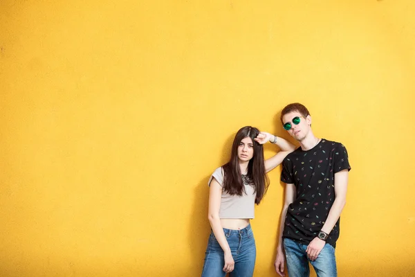 Giovane coppia cercando fresco su parete gialla — Foto Stock