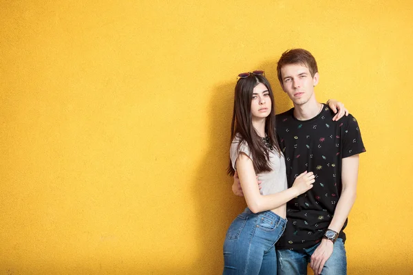 Muito legal jovem casal na parede amarela — Fotografia de Stock