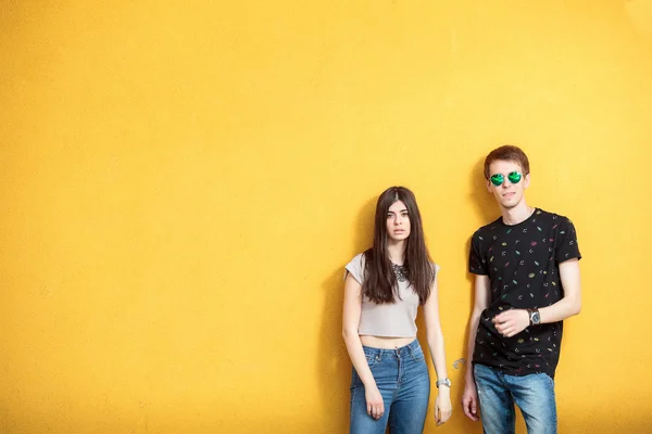 Pareja joven en la pared amarilla —  Fotos de Stock