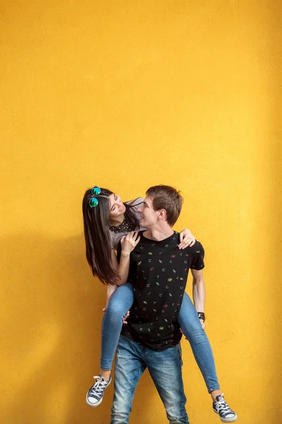 Casal de amor olhando um para o outro na parede amarela — Fotografia de Stock