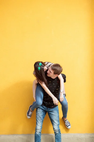Unga par ha kul utanför på en gul vägg — Stockfoto