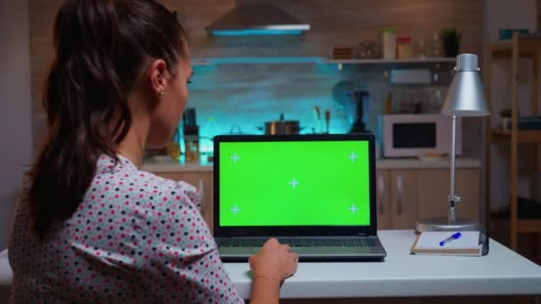 Vrouw op zoek naar laptop met groene mockup — Stockvideo