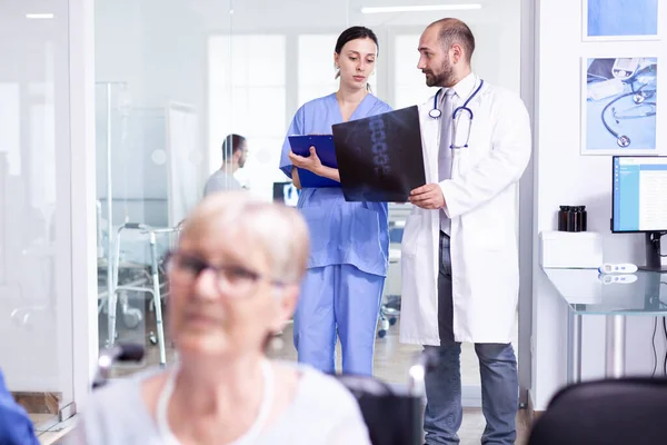 Läkare som förklarar diagnos för sjuksköterska i väntrummet — Stockfoto