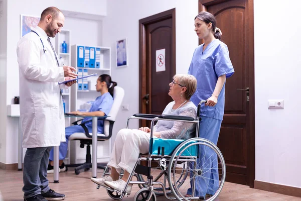 Sanitäter im Gespräch mit behinderter Seniorin — Stockfoto