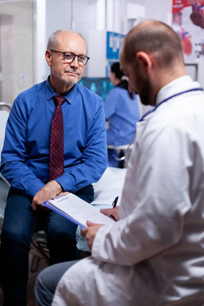 Old man answering doctor questionnaire — Stock Photo, Image