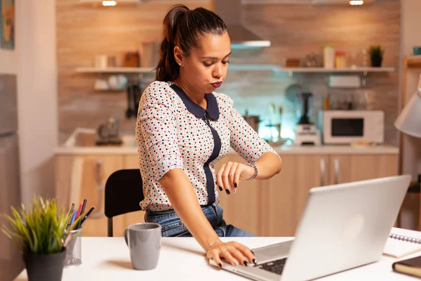 Mulher verificando relógio durante o trabalho de horas extras — Fotografia de Stock