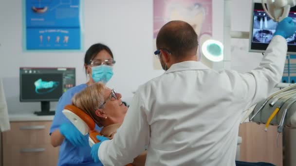 牙科诊所坐在牙医椅子上的老年妇女 — 图库视频影像