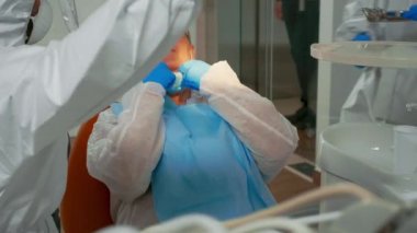 Hastayı muayene etmek için kapak lambası kullanan dişçi teknisyeni.