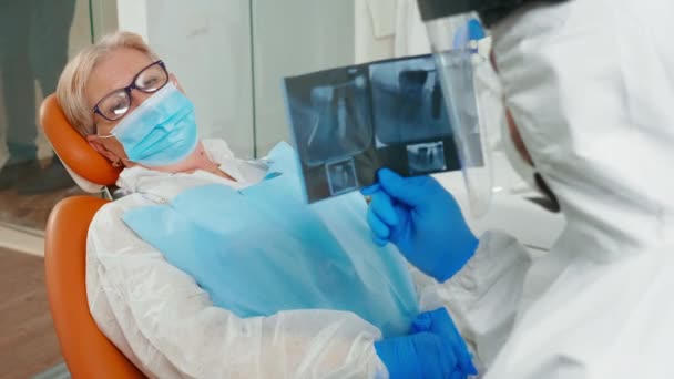 Lekarz z osłoną twarzy przeglądający panoramiczny obraz rentgenowski zębów — Wideo stockowe
