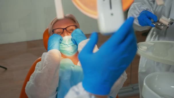 Женщина в стоматологической хирургии лечится зубной дрелью во время ковида-19 — стоковое видео