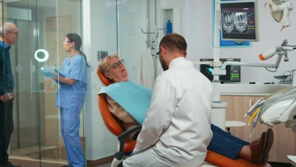 Ортодонт разговаривает с пациентом с зубной болью — стоковое видео