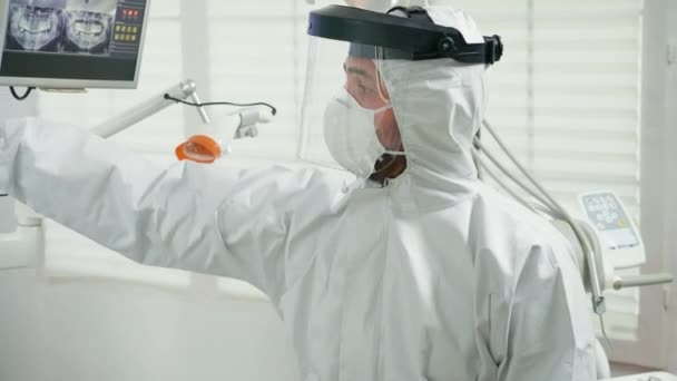 Портрет стоматолога зі щитом для обличчя, що пояснює, як тримається рентгенівський знімок — стокове відео