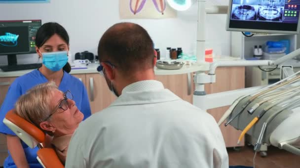 牙科医生和助理与现代牙科诊所的病人一起工作 — 图库视频影像