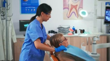 Hemşire hastayı hazırlıyor. Diş önlüğü takıyor.