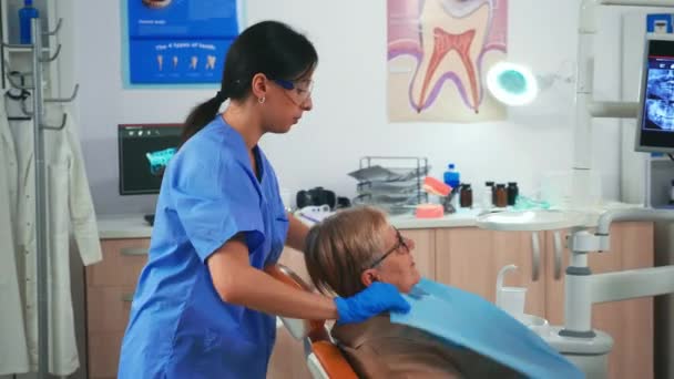 Pielęgniarka przygotowuje pacjenta do układania śliniaczka dentystycznego — Wideo stockowe