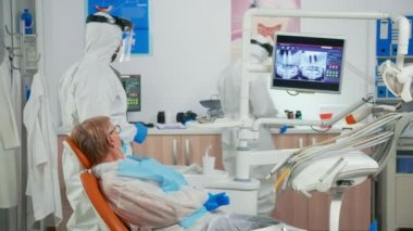 Koruyucu kıyafetli Stomatolog diş radyografisini açıklıyor