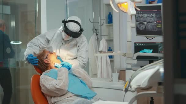 Dentista com rosto shiled tratamento de dentes para a mulher idosa — Vídeo de Stock
