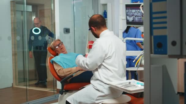 Dentista explicando la cirugía usando un modelo de yeso de la mandíbula — Vídeos de Stock