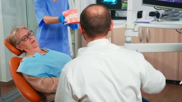 Dentista che tiene la mandibola dentale parlando con il paziente — Video Stock