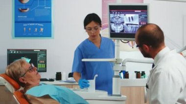 Diş implantlarını gösteren dijital ekrandaki doktor.