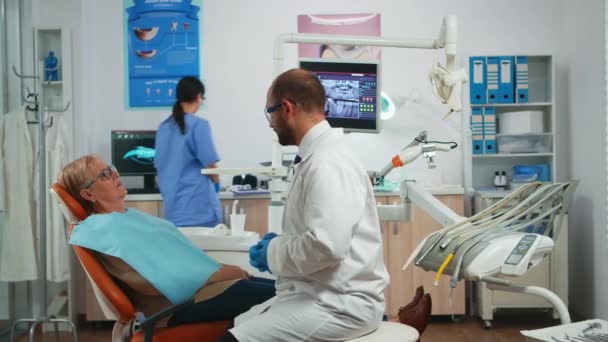 Врач-стоматолог объясняет процесс вмешательства — стоковое видео