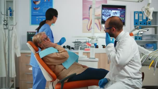 Gammal patient vidrör kinden visar tand med smärta — Stockvideo