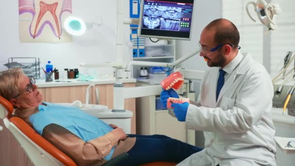 Explicando o procedimento usando modelo de dentes dentários — Vídeo de Stock
