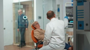 Stomatolog röntgeni açıklayan dijital ekrana işaret ediyor