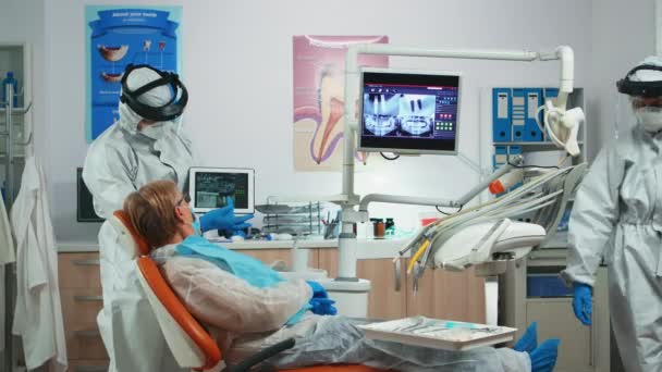 Dentista en bata examinando imagen de rayos X en tableta — Vídeos de Stock