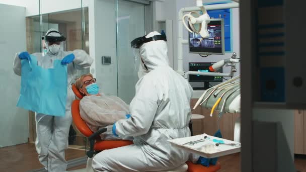 Enfermera en mono poniendo babero dental a la mujer durante el examen — Vídeos de Stock