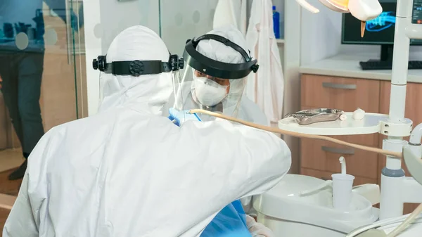 Dentists with face shield cleaning and examining patient teeth — Stock Photo, Image