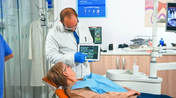 Ортодонт в перчатках держит планшет с предложением лечения — стоковое фото