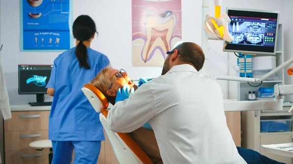Стоматолог, що працює в стоматологічному відділенні з медсестрою і чоловіком, що лежить пацієнт — стокове фото