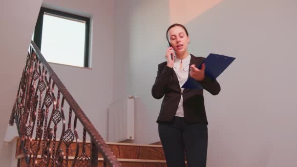 Бізнес-леді розмовляє по телефону стоячи на сходах — стокове відео