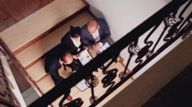 Proje ekibinin üst görüntüsü merdivenlerde oturan belgelere bakıyor