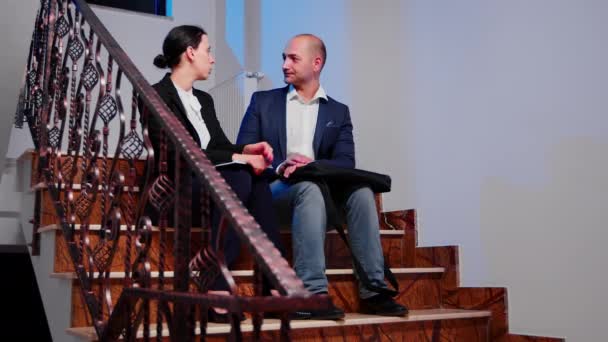 Партнеры обсуждают возможность сидеть на лестнице в корпоративном бизнесе — стоковое видео