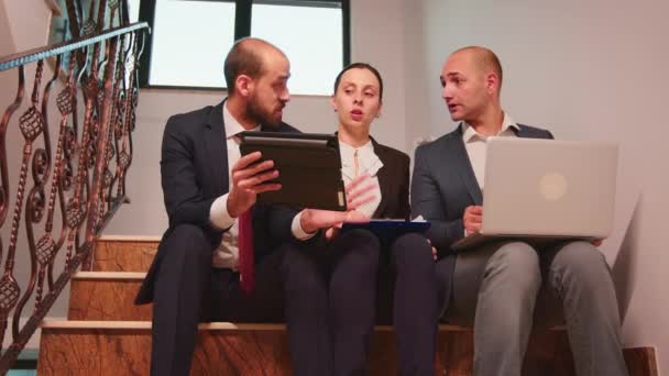 Compañeros discutiendo planes sentados en escaleras — Vídeo de stock